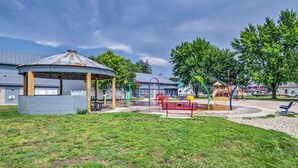 Un parque infantil con un quiosco, columpios y un banco rojo.
