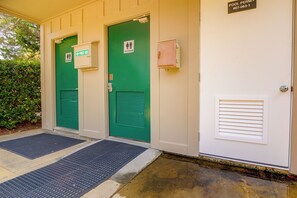 A building entrance with two green doors, each marked with a restroom sign and a first aid sign. - Palmetto Dunes Villa w/ Deck & Lagoon Views! (Hilton Head Island)