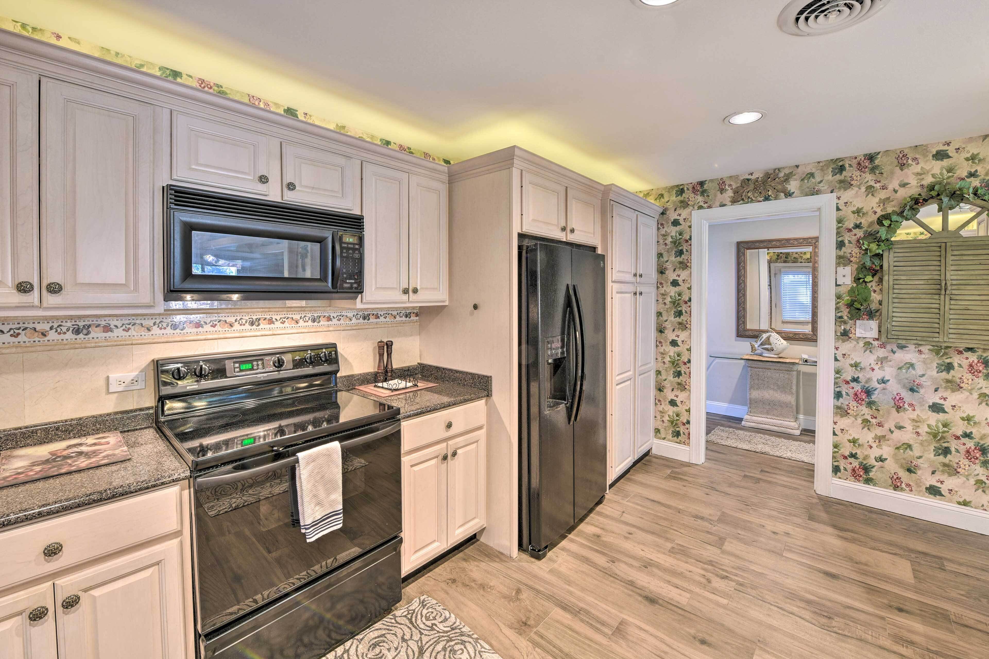 A kitchen with white cabinets, a stainless steel refrigerator, and a microwave.