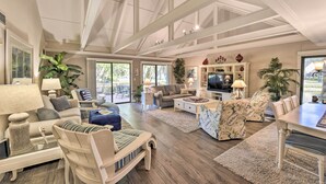A spacious living room with a high ceiling, a television, and a dining area with a table and chairs.