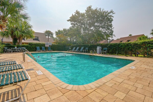 A rectangular swimming pool with a tiled deck, surrounded by lounge chairs and a palm tree. - Palmetto Dunes Villa w/ Deck & Lagoon Views! (Hilton Head Island)