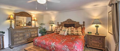 A bedroom with a large bed, a wooden bench, a ceiling fan, and two nightstands with lamps.