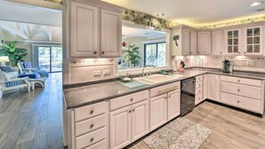 A kitchen with white cabinets, a granite countertop, and a large window.