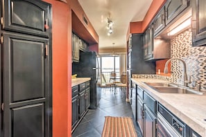 A modern kitchen with dark cabinetry, a tiled backsplash, and a central island. - Arkansas Retreat Near Lake Hamilton w/ Pool Access (Hot Springs)