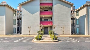 A multi-story building with a central entrance, a parking lot in front, and a red awning over the entrance. - Arkansas Retreat Near Lake Hamilton w/ Pool Access (Hot Springs)