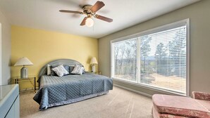 A bedroom with a bed, two bedside lamps, a ceiling fan, a large window with blinds, and a carpeted floor. - Arkansas Retreat Near Lake Hamilton w/ Pool Access (Hot Springs)