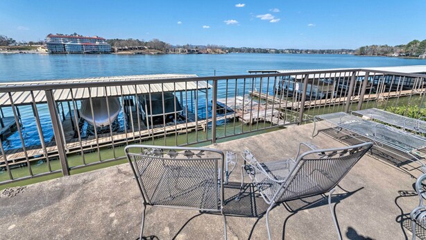 A waterfront patio with metal chairs and a view of a cruise ship docked across the water. - Arkansas Retreat Near Lake Hamilton w/ Pool Access (Hot Springs)
