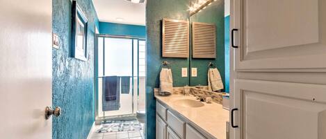 A bathroom with a double sink, vanity, and a large mirror. There is a door leading to a shower area.