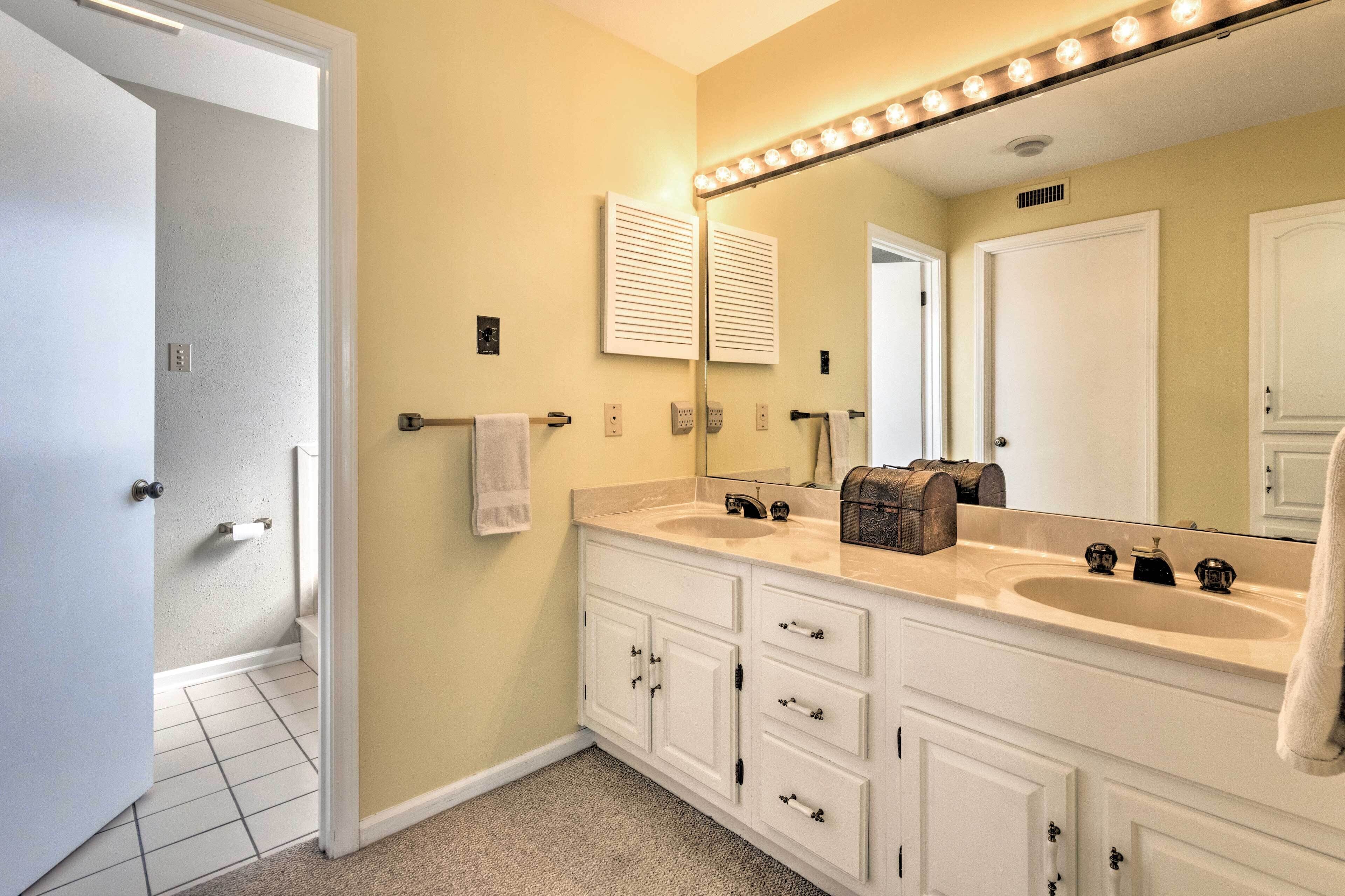 Un bagno con doppio lavabo, uno specchio grande con illuminazione e un portasciugamani.