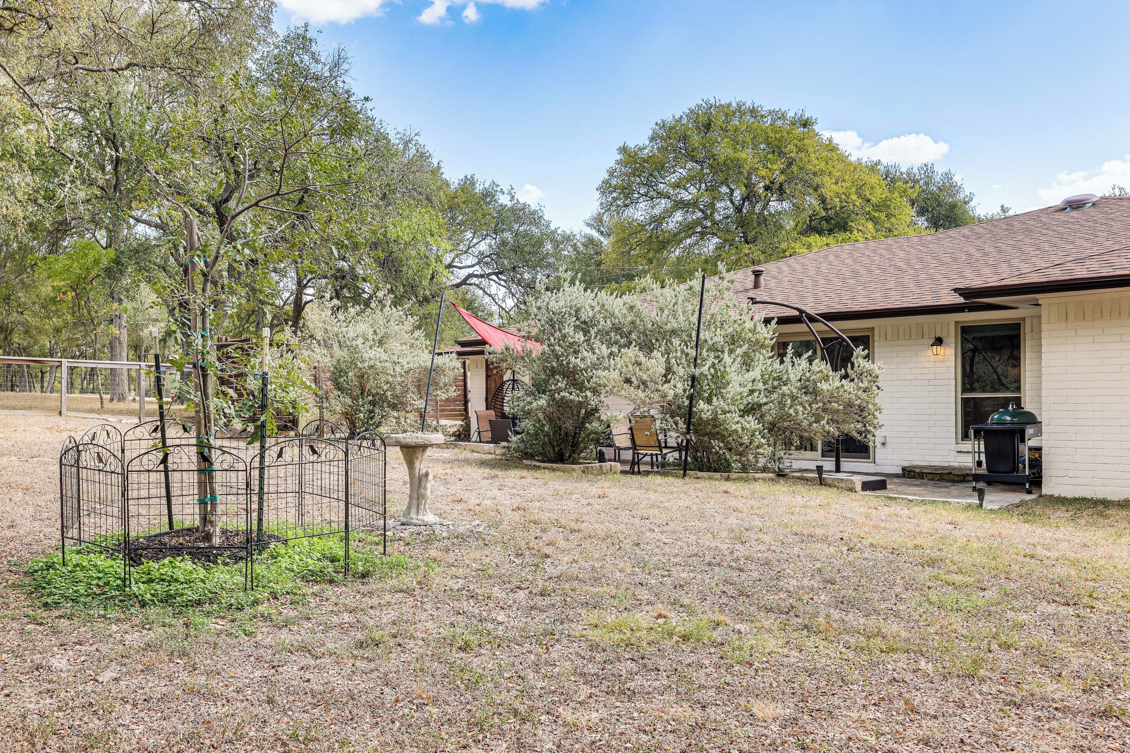 A residential property with a fenced yard, a patio with outdoor furniture, and a house with a chimney.