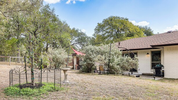 A residential property with a fenced yard, a patio with outdoor furniture, and a house with a chimney. - Gorgeous San Marco Home w/ Patio & Grill! (San Marcos)