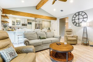 A spacious living area with a sofa, a coffee table, and a leather chair. A large wall clock is visible. - Gorgeous San Marco Home w/ Patio & Grill! (San Marcos)