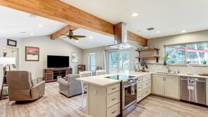 A modern kitchen with wooden beams, a dining area with a sofa, and a TV. - Gorgeous San Marco Home w/ Patio & Grill! (San Marcos)