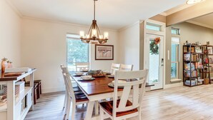 A dining area with a wooden table, white chairs, and a chandelier. - Gorgeous San Marco Home w/ Patio & Grill! (San Marcos)