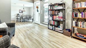 A spacious room with a dining area, a bookshelf filled with books, and a wooden floor. - Gorgeous San Marco Home w/ Patio & Grill! (San Marcos)