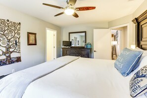 A bedroom with a bed, a ceiling fan, a dresser, a mirror, and a door leading to another room. - Gorgeous San Marco Home w/ Patio & Grill! (San Marcos)