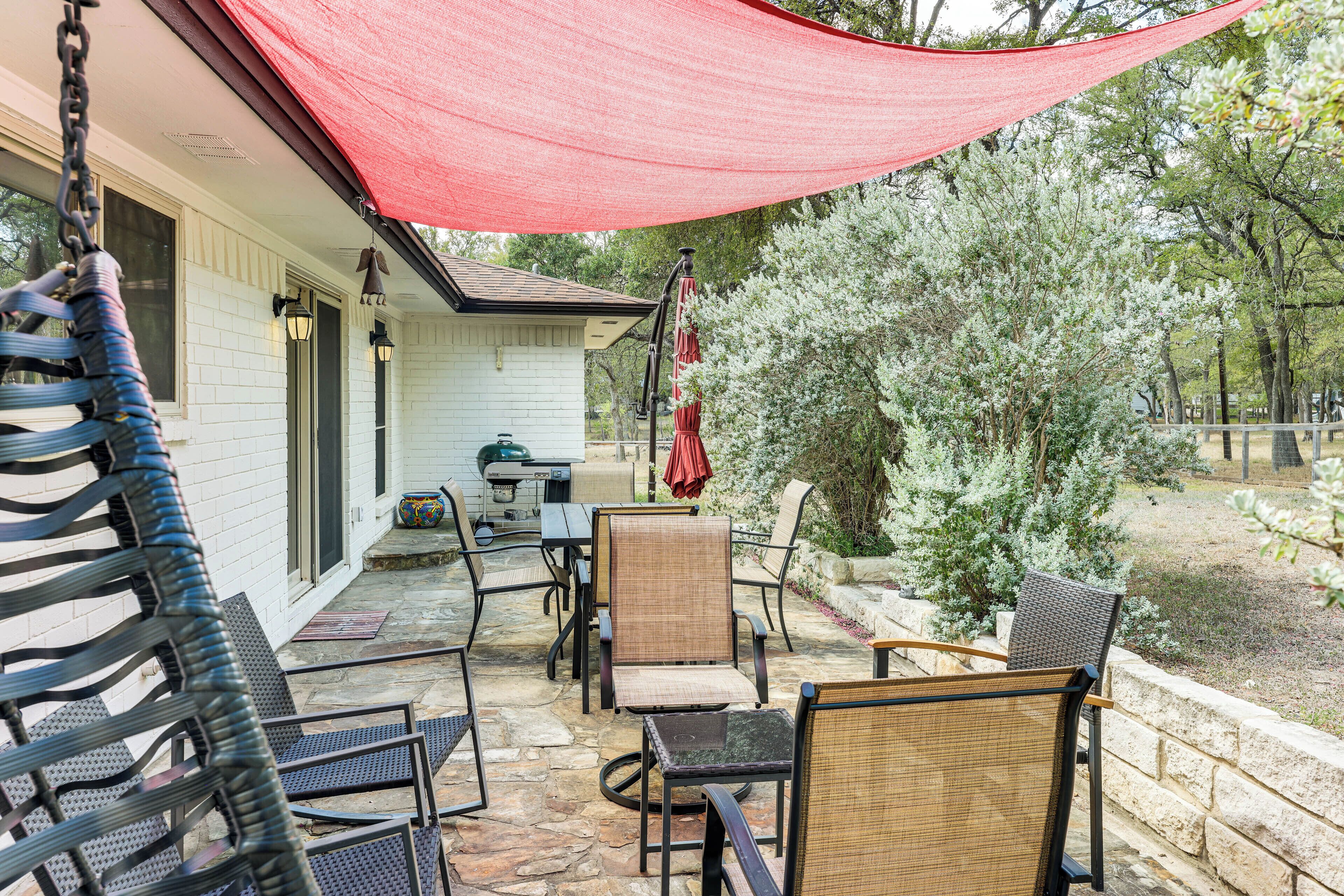 An outdoor patio with wicker chairs, a table, and a red canopy.