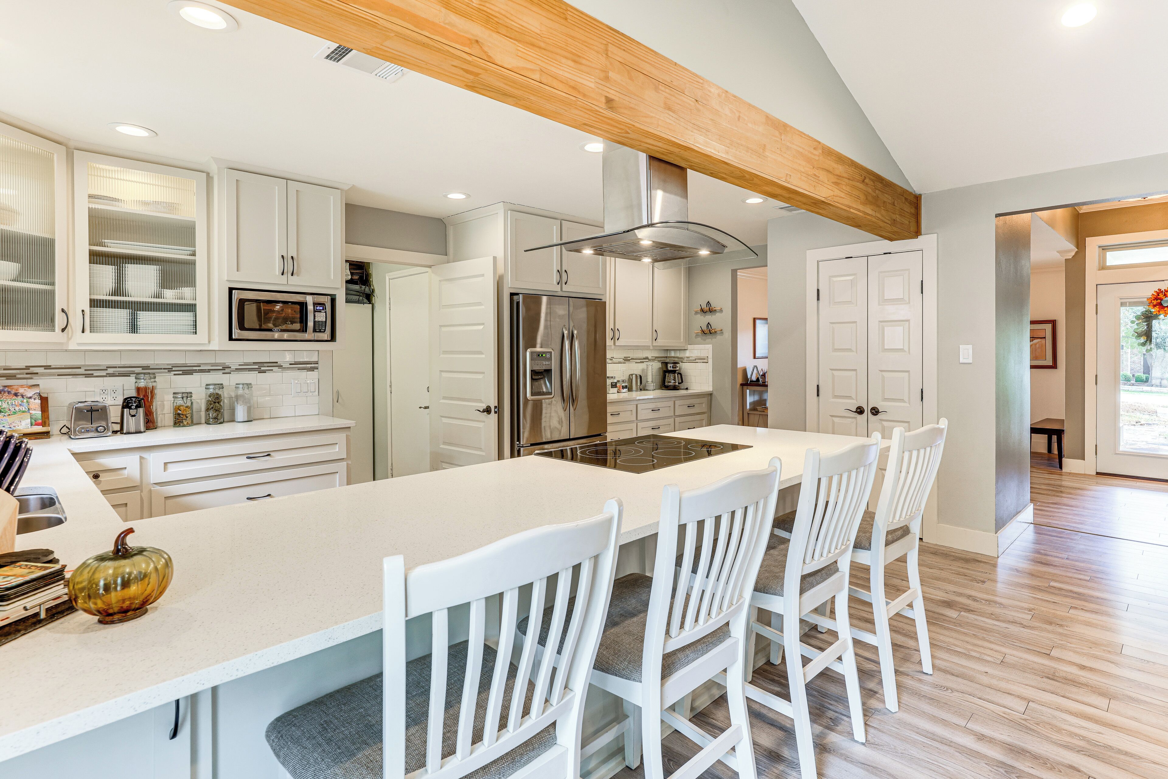 A modern kitchen with white cabinetry, stainless steel appliances, and a large island with bar stools.