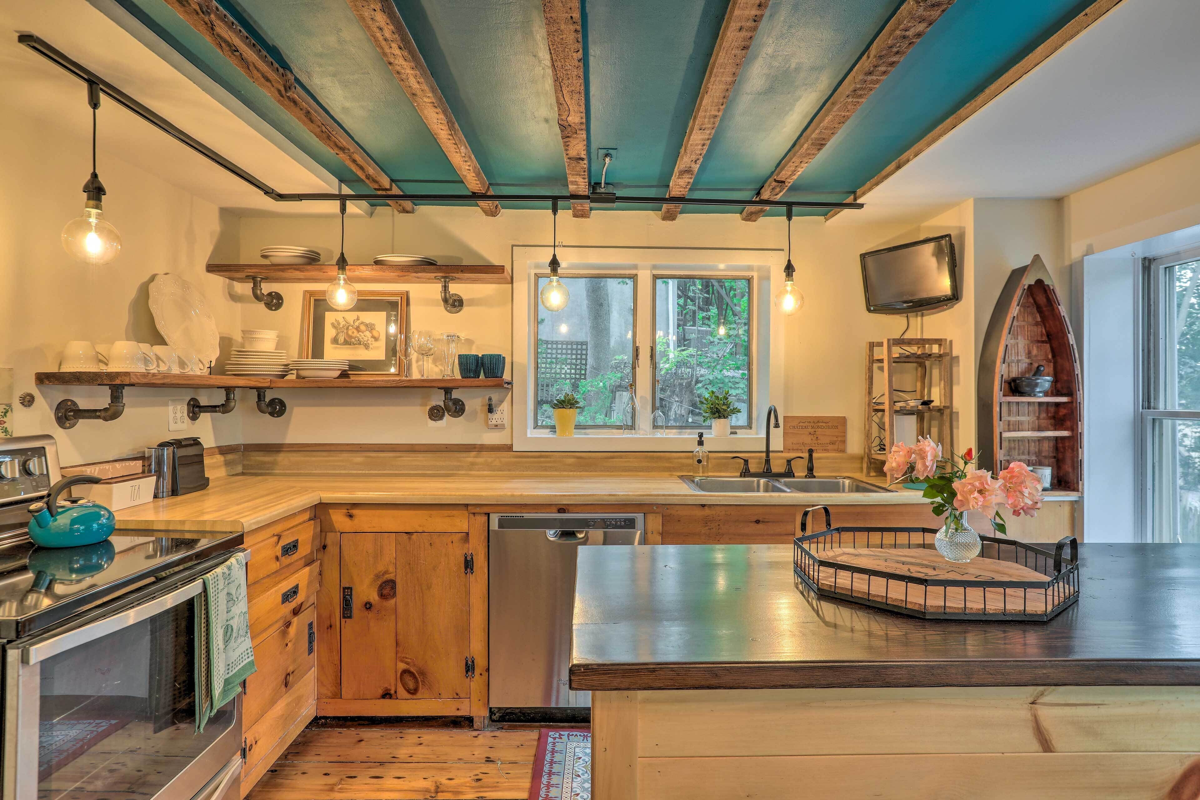 Una cocina con armarios de madera, lavavajillas, estufa y un ventanal grande.