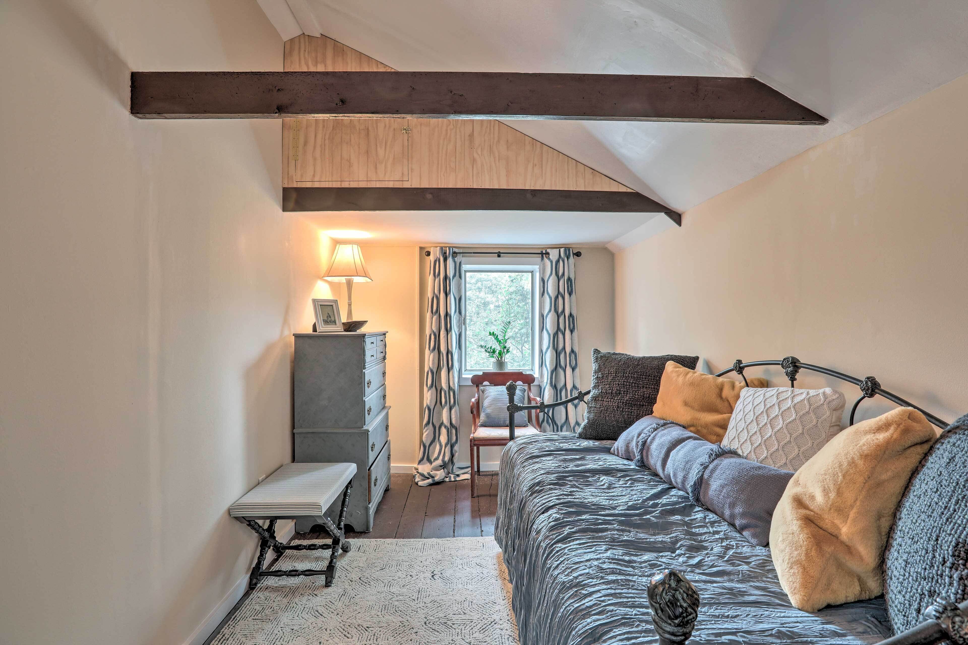 A cozy bedroom with a bed, bedside table, and a window with curtains.