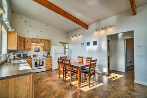 A kitchen with wooden cabinets, a granite countertop, a dining table with chairs, and a tiled floor. - Secluded Getaway w/ Deck, Steps to Fritz Creek! (Homer)