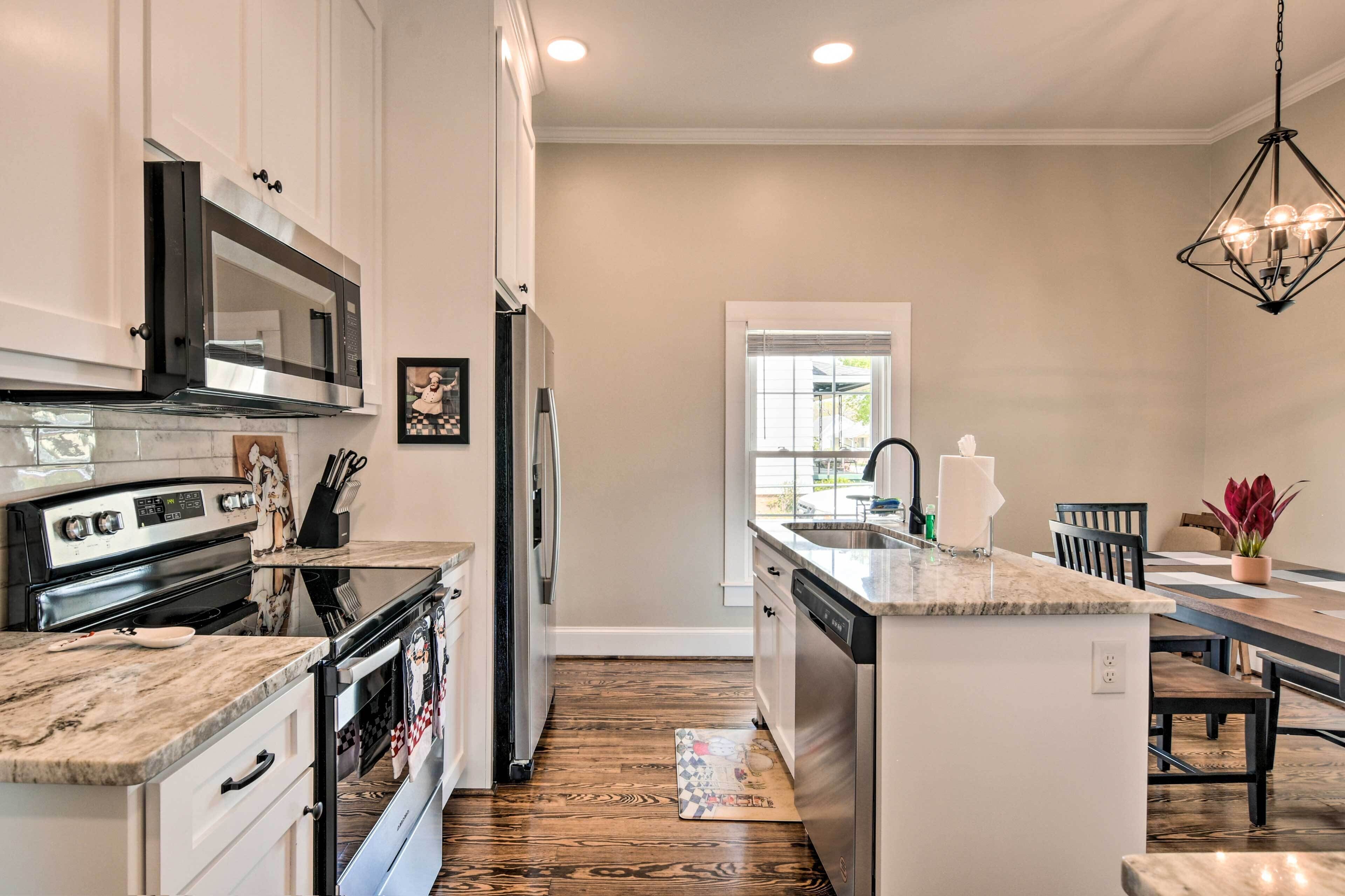 A modern kitchen with a central island, stainless steel appliances, and a dining area with a chandelier.