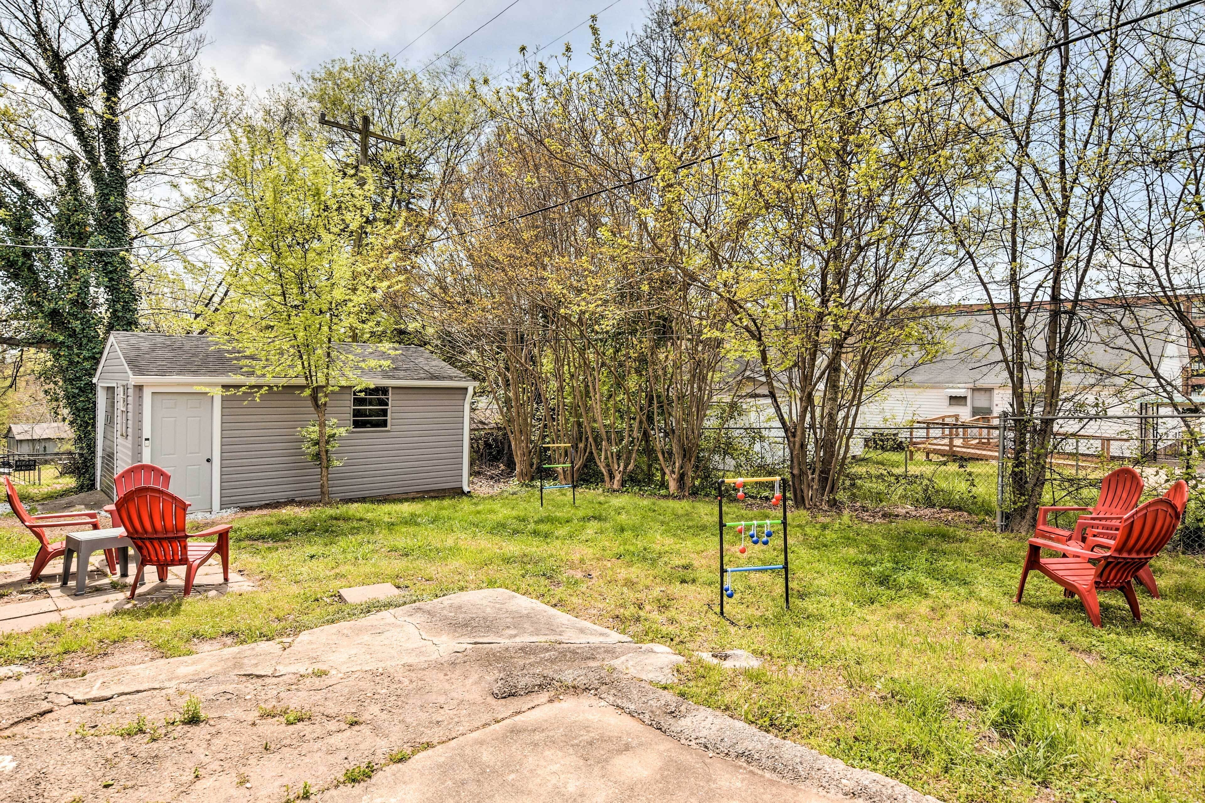 A backyard with a small shed, red Adirondack chairs, a concrete patio, and a trampoline.