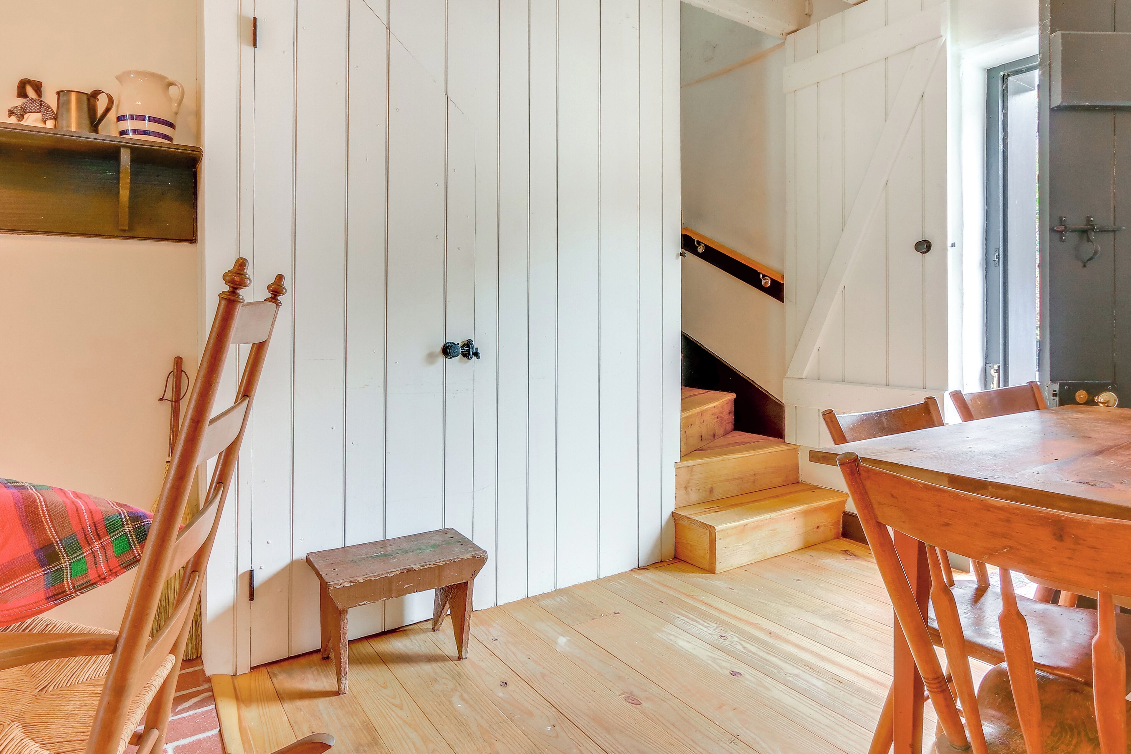 Ein Holzesstisch mit Stühlen, einer Bank und einer Treppe zu einer Erkerzone.