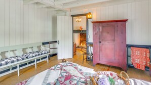 Ein gemütlicher Raum mit einer hölzernen Bank, einem Patchwork-Quilt, einem roten Schrank und einem Kamin.