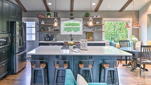 A modern kitchen with dark cabinets, stainless steel appliances, and a central island with bar stools.