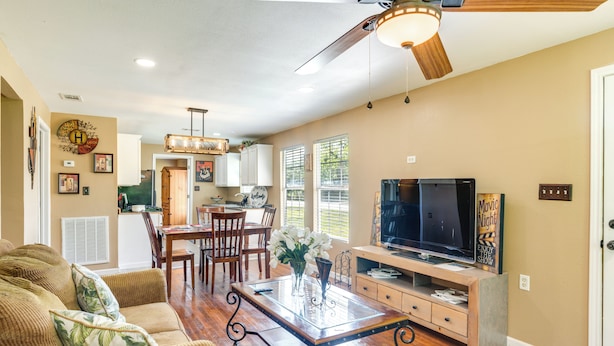 A living room with a sofa, coffee table, TV, and a dining area with chairs and a table. - Kayak, Fish & Golf - Charming Victoria Home! (Bloomington)