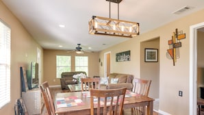 A dining area with a wooden table and chairs, a ceiling fan, and a chandelier. - Kayak, Fish & Golf - Charming Victoria Home! (Bloomington)