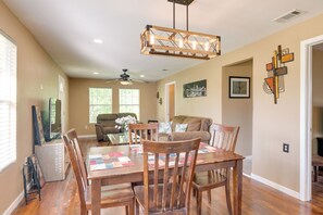 A dining area with a wooden table and chairs, a ceiling fan, and a chandelier. - Kayak, Fish & Golf - Charming Victoria Home! (Bloomington)