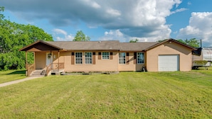 A single-story house with a front porch, a garage, and a well-maintained lawn. - Kayak, Fish & Golf - Charming Victoria Home! (Bloomington)