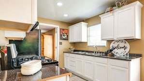 A kitchen with white cabinets, a granite countertop, a stove, and a welcome sign. - Kayak, Fish & Golf - Charming Victoria Home! (Bloomington)