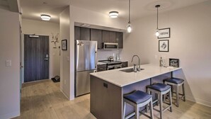 A modern kitchen with a central island, stainless steel appliances, and bar stools. - Chic Bozeman Apartment - 1 Block Off West Main St! (Bozeman)
