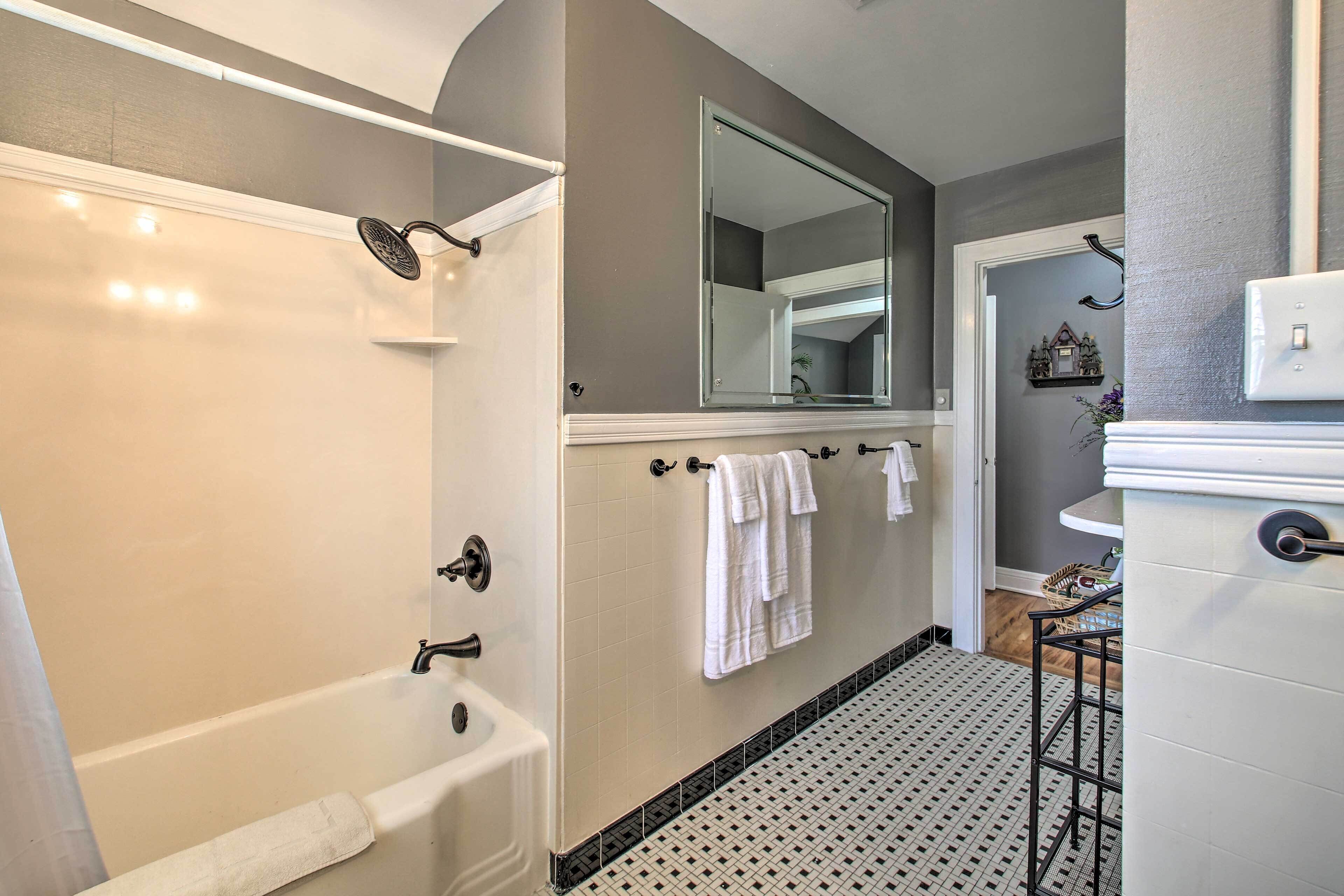 Un baño con bañera, ducha, lavamanos y espejo.
