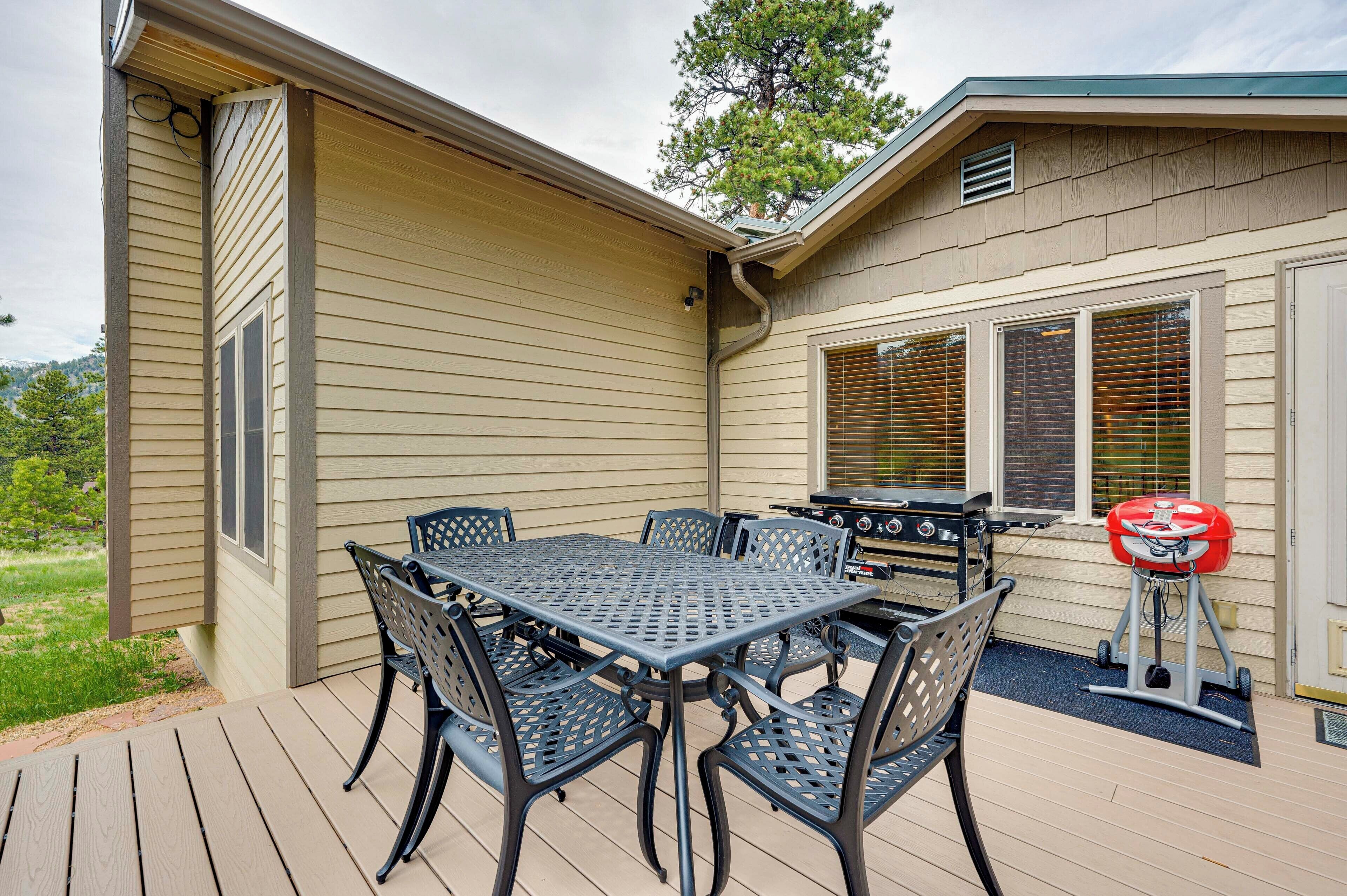An outdoor patio with a table and chairs, a grill, and a red cooler.