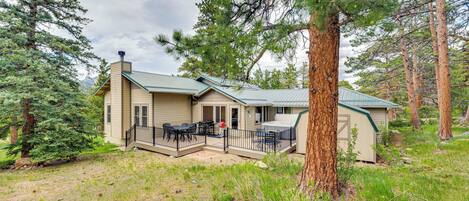 A lodge with a covered patio, outdoor seating, and a view of the surrounding forest.