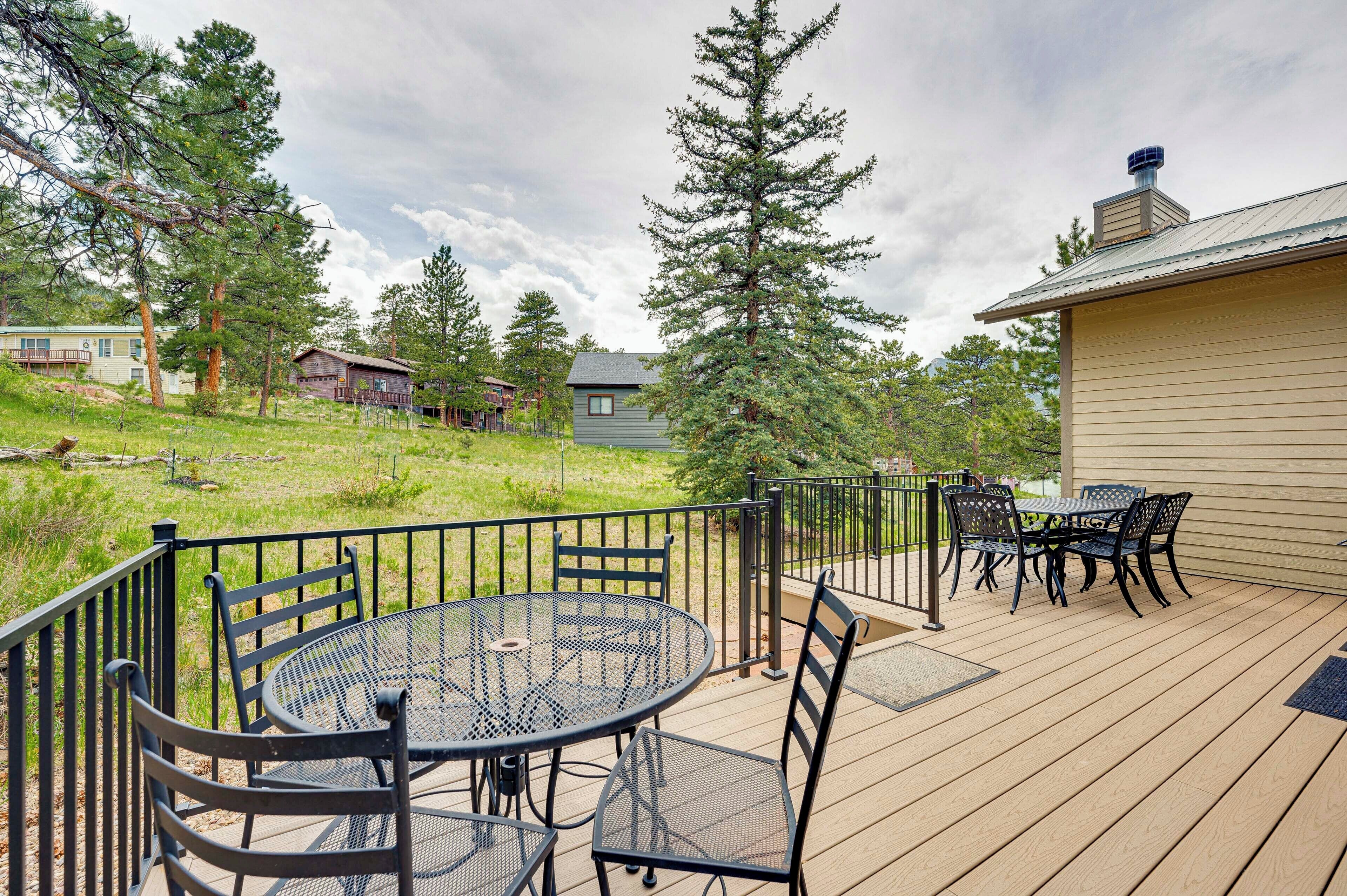 A wooden deck with a round table and chairs, surrounded by a metal railing.