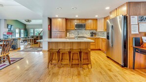 Une cuisine moderne avec des meubles en bois, des appareils en acier inoxydable et un îlot central doté de tabourets de bar.
