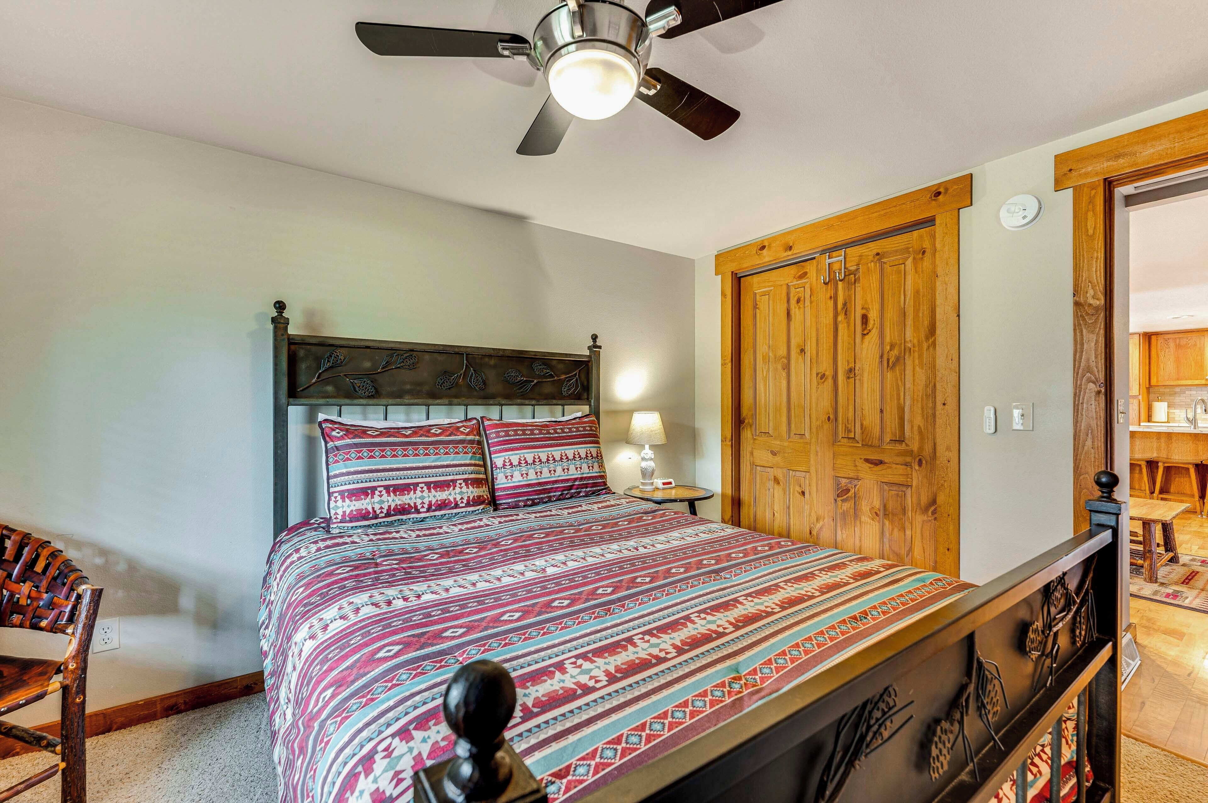 Ein Schlafzimmer mit Bett, Holzschrank, Deckenventilator und Nachttisch mit Lampe.