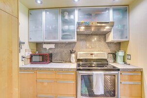 Una cocina equipada con microondas, tostadora, cafetera, horno y alacenas.