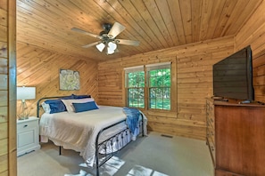 A wooden cabin bedroom with a bed, nightstand, dresser, and a ceiling fan. - Fish, Hike & Relax: Forest-view Morovian Falls Gem (Moravian Falls)