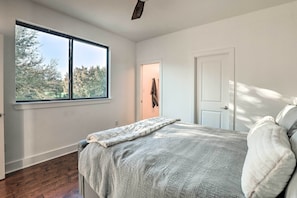 Un dormitorio con un ventanal grande, una cama con una manta y una puerta.
