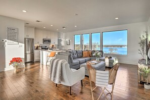A spacious living area with a grey sofa, a coffee table, and a view of the outdoors. - Entire Home w/ Lake Granbury Views + Game Room! (Granbury)
