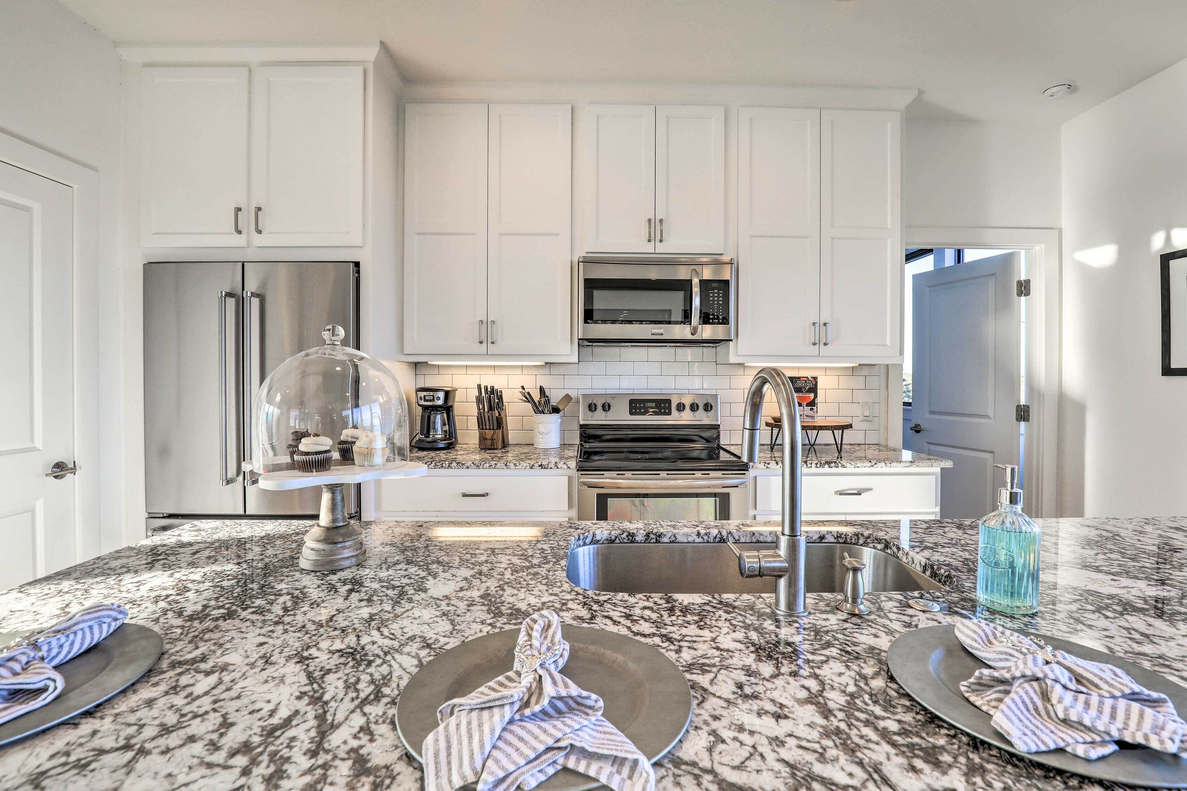 A modern kitchen with white cabinets, stainless steel appliances, and a granite countertop.