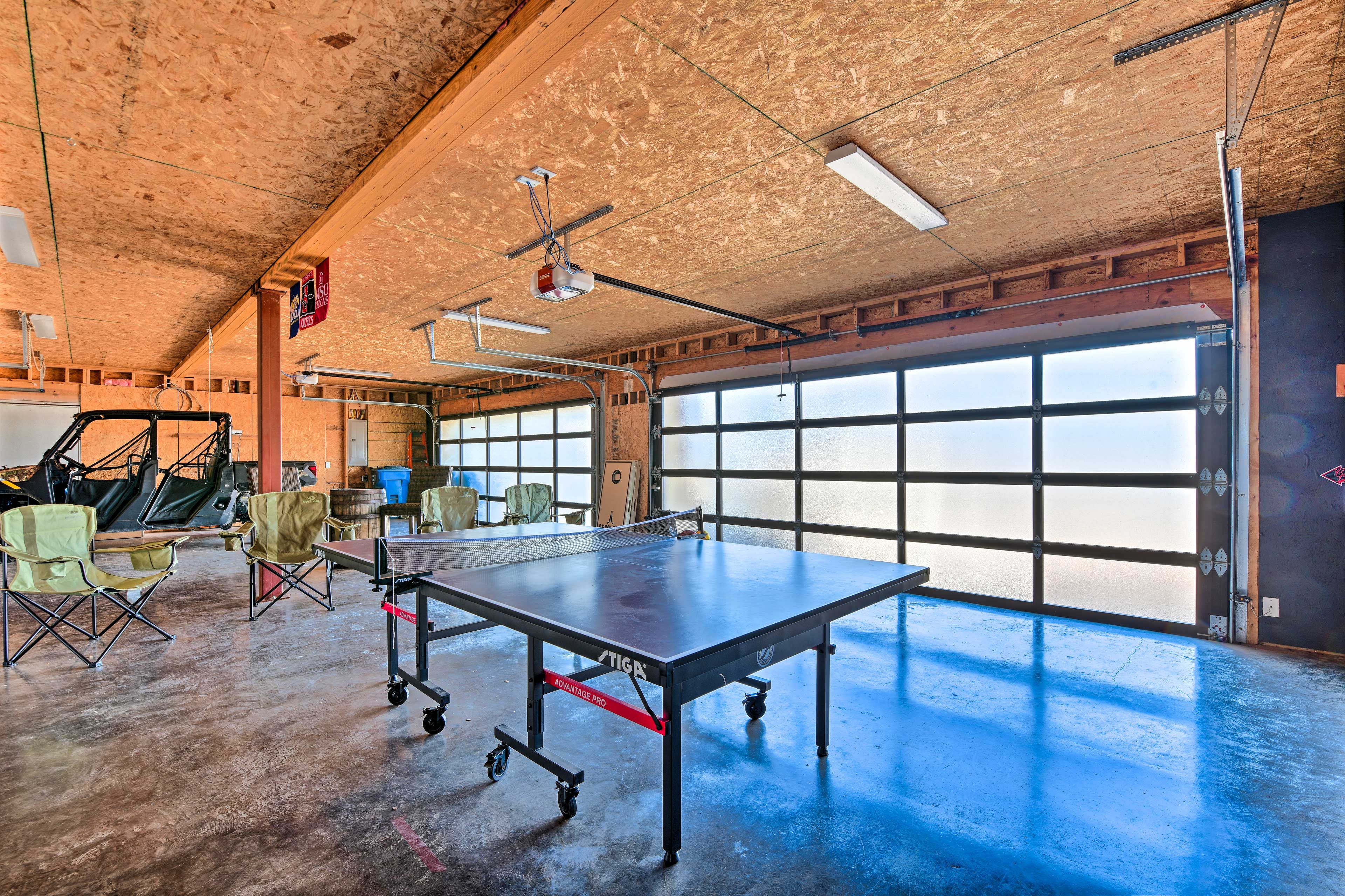 Une table de ping-pong dans une pièce spacieuse, dotée de grandes fenêtres, d’un projecteur et de chaises pliantes.