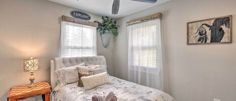 Un dormitorio con cama, ventilador de techo, mesita de noche con lámpara y un letrero que dice "EXPLORE".
