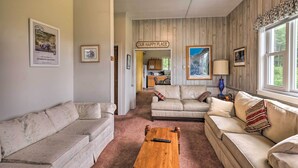 Un salon chaleureux avec deux canapés, une table basse en bois et une pancarte sur laquelle on peut lire : « NOTRE PETIT COIN DE BONHEUR ».